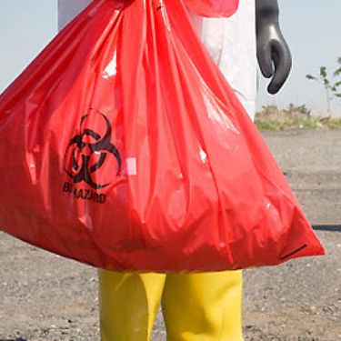 A Clinical Waste Member of Staff Holding a Red Bag Containing Hazardous Waste