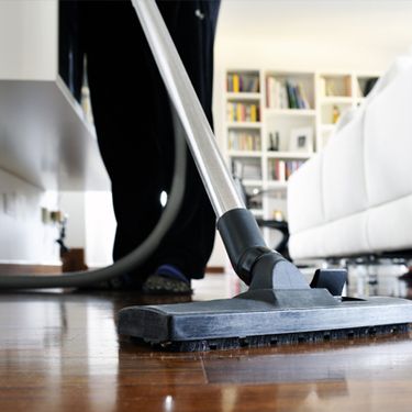 A Dark Wooden Living Room Floor Being Hoovered With A Vacuum Cleaner