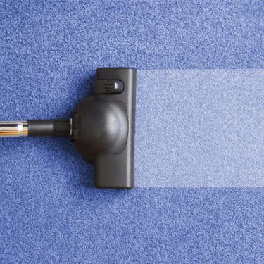 A Dirty Blue Carpet Being Hoovered With A Vacuum Cleaner